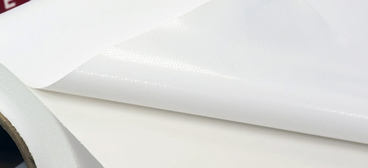 A close-up of the Indoor Wall Decal material used for the Euro 2024 wall chart. The image shows layers of the glossy white vinyl, highlighting its texture with a subtle dot pattern visible on the surface. This demonstrates the material's unique adhesive technology that allows for bubble-free application and easy repositioning.